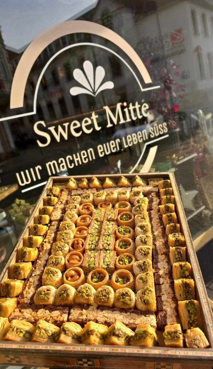 Holzbox mit gemischtem Baklava vor dem Sweet-Mitte-Schriftzug am Schaufenster in Jena