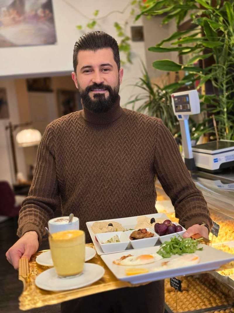 Inhaber Hassan Hayyawi serviert ein Frühstückstablett im Café